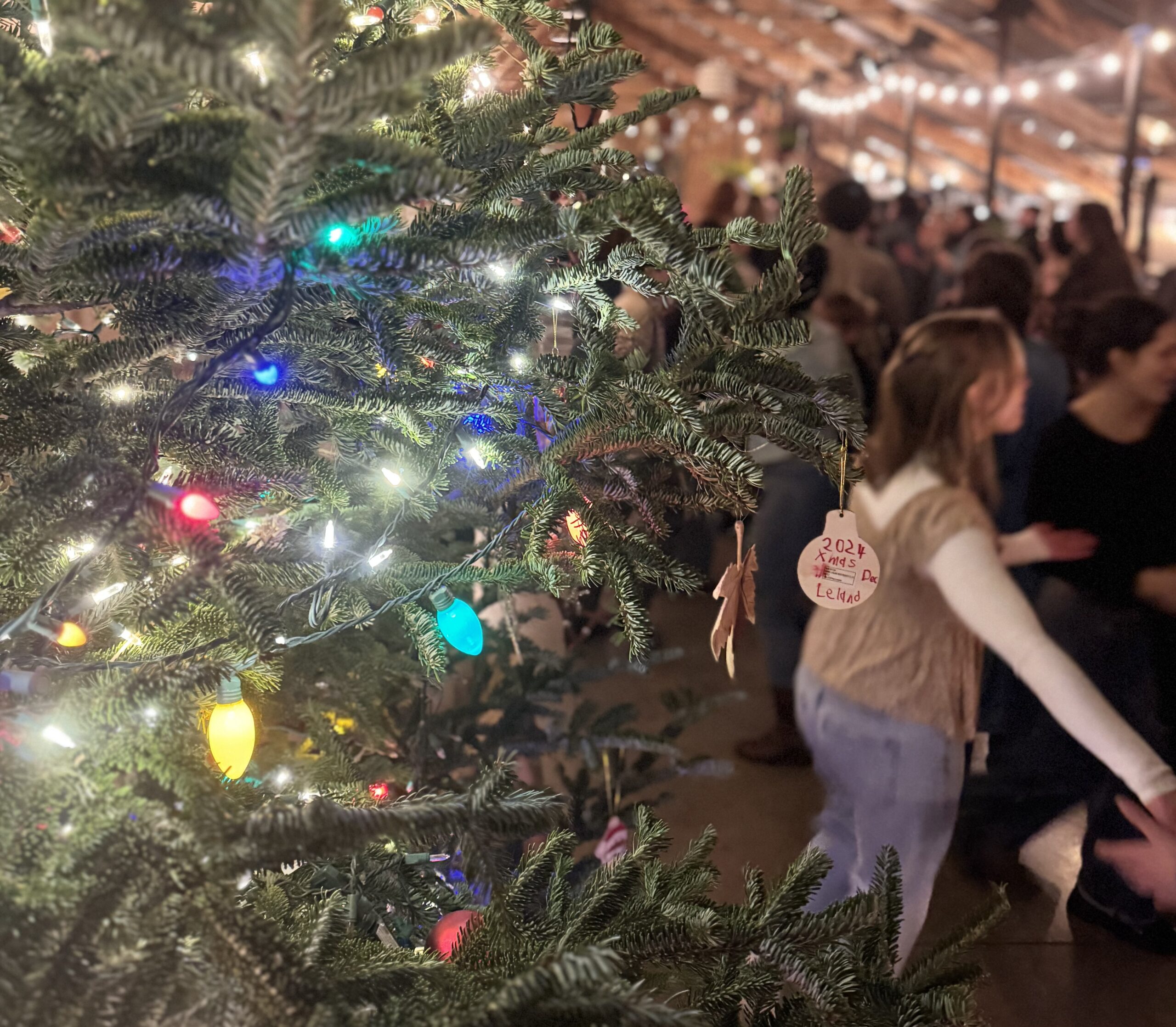 Decorated Christmas tree in the foreground with square dancers in the background at Stone Bend Farm in Newfield, New York.